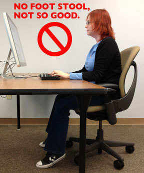 Mujer trabajando con el ordenador en el escritorio sin taburete para los pies, sólo los dedos tocan el suelo.